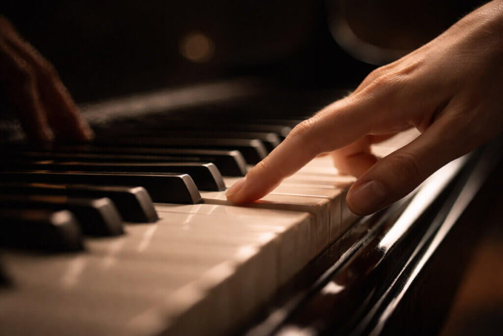 Nomi corti femminili: un dito sfiora il tasto di un pianoforte, simbolo di grazia.